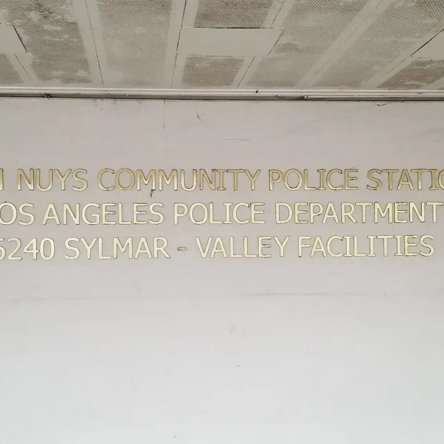 Gold letters on a wall sign for LAPD North Hollywood Community Police Station and Valley facilities