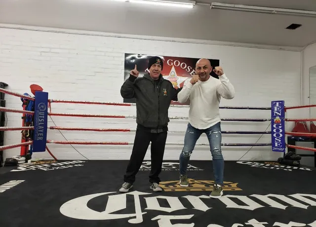 Two men are standing in a boxing ring with the word corona on the floor