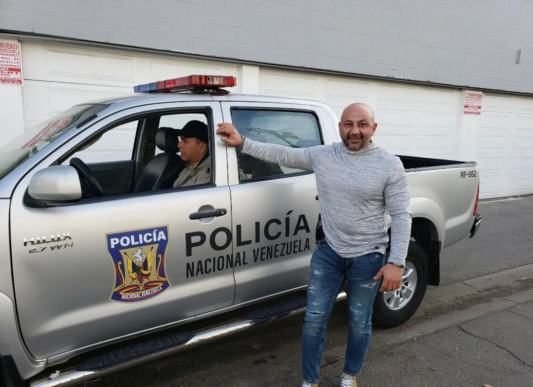 A man is standing in front of a silver police truck