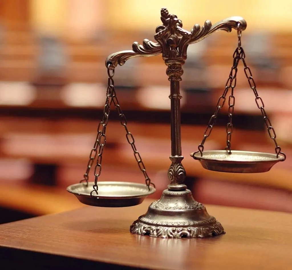 A scale of justice sits on a wooden table